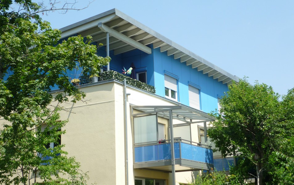 Foto eines mehrgeschossigen Gebäudes mit weiß-blauer Fassade.