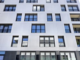 Foto des Gebäudes SKAIO Stadtsiedlung in Heilbronn. Man sieht ein mehrgeschossiges, weißes Gebäude und einen Fassadenausschnitt davon.