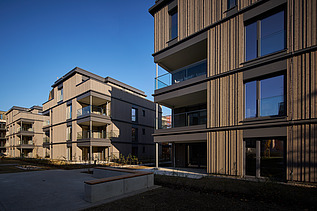 Foto eines mehrgeschossigen Wohngebäudes mit Holzfassade.