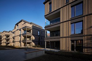 Foto eines mehrgeschossigen Wohngebäudes mit Holzfassade.