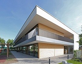 Außenaufnahme der Kita in Frankfurt. Man sieht ein Gebäude aus Holz mit Flachdach.