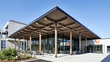Außenaufnahme des Mitarbeiterrestaurants Viessmann in Allendorf: Zu sehen ist ein Gebäude mit vielen Glasflächen und Flachdach mit großem Holzvorsprung.