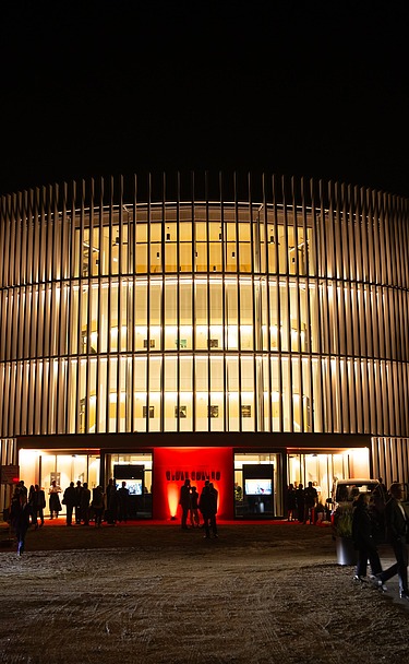 Nachtaufnahme des Globe Theaters in Coburg. Zu sehen ist ein rundes Gebäude aus Holz.
