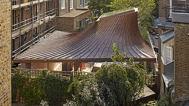 Foto von einem kleinen Gebäude mit Kuppeldach und inmitten mehrgeschossiger Bauten