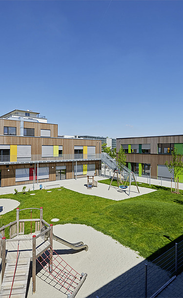 Elementary school Munich Photo of a wooden school from the outside. You can see the wooden building and the garden area.