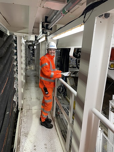 Foto einer jungen Frau in Arbeitskleidung auf der Baustelle. Sie steht am Geländer.