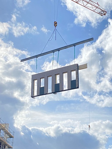 Foto eines schwebenden Holzrahmenbauelements am Kran. Baustelle Büro T3 von ZÜBLIN Timber.