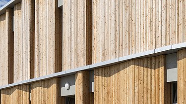 Außenaufnahme der Kindertagesstätte Campeon Infineon in Neubiberg. Man sieht einen Gebäudeausschnitt und die Holzfassade.