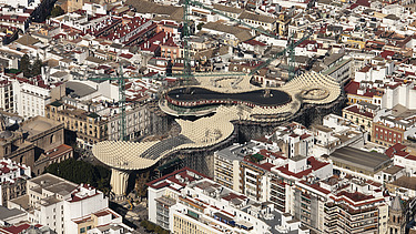 Photo of an aerial view of Seville. You can see the mushroom-like wooden construction of the Metropol Parasol Sevilla marketplace roof.