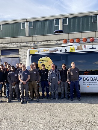 Foto von gewerblichen ZÜBLIN Timber Kollegen, die vor dem BG BAU-Bus stehen.