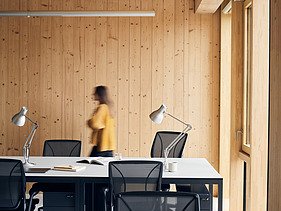 Photo of an interior of the Black and White office in London. You can see wooden surfaces and a woman.