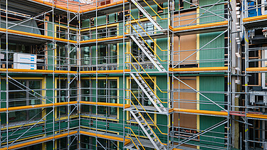 Photo of the VINZENT building shell in Munich. You can see a scaffolded, multi-storey building.