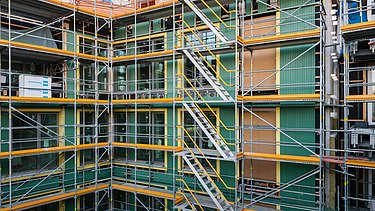 Photo of the VINZENT building shell in Munich. You can see a scaffolded, multi-storey building.