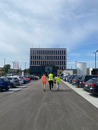 Three people walking towards the ZÜBLIN Timber office building
