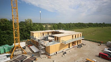 Construction site photo showing the assembly of the first cross-laminated timber elements.