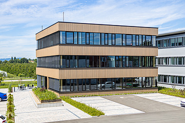 Foto eines Holzgebäudes mit Holz-Glasfassade und Flachdach.