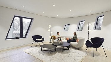 Photo of an interior. Two women are sitting on a light-colored couch.