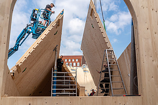 Photo of a timber construction site. Two carpenters are assembling LENO elements.