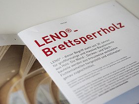 Foto der Innenseite der Broschüre Holzbauelemente von ZÜBLIN Timber. Man sieht links LENO als Gewölbebalken und rechts die Überschrift LENO-Brettsperholz mit Text.