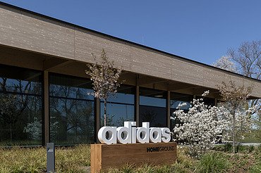 Homeground adidas Herzogenaurach Photo of a building with a flat roof. In front of it is a sign with the inscription adidas