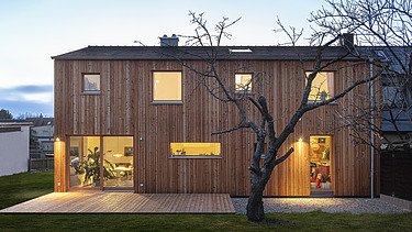 Photo of a modern wooden house. Dusk.