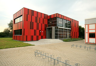Foto einer Außenansicht der Einhardschule in Seligenstadt. Man sieht eine rote Fassade.