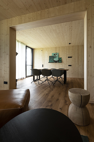 Photo of a living room with lots of wooden surfaces. Table, chairs and stools.