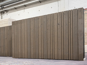 Photo of a standing LENO ADD exterior wall in the ZÜBLIN Timber production hall. It has a continuous timber façade installed.