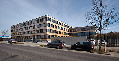 Photo of the Flexim Berlin office building from the outside. You can see a large wooden building with a wooden façade and flat roof.