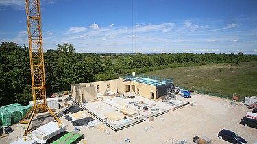 Baustellenfoto, auf dem die Montage der ersten Brettsperrholzelemente zu sehen ist.