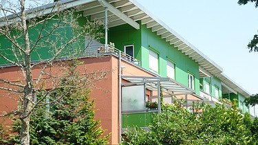 Photo of a multi-storey building with an orange-green façade.