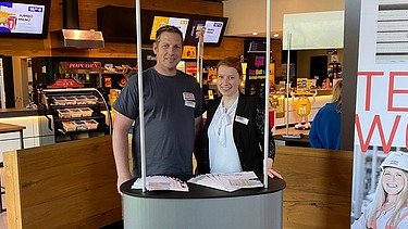 Fotos eines Messestandes von ZÜBLIN Timber. Zwei Personen sind zu sehen.