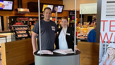 Photos of a ZÜBLIN Timber exhibition stand. Two people can be seen.