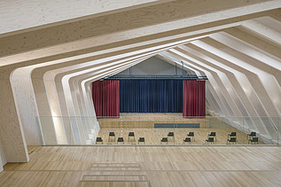 Foto eines Bühnenraumes mit großer sichtbarer Rippen-Holzkonstruktion.