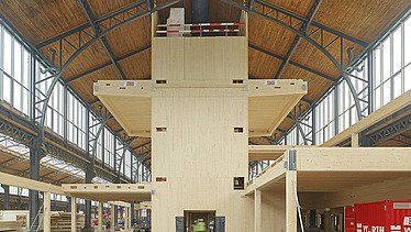 Photo of the hall of the Gare Maritime Brussels. Huge, open hall space with wooden roof construction and wooden building.