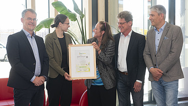 Aktuelles ZÜBLIN Timber Foto mit fünf Personen. Zwei halten das Zertifikat Holz von Hier für den Büroneubau von ZÜBLIN Timber.