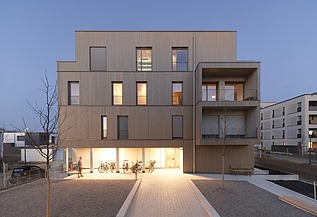 Nachtaufnahme eines mehrgeschossigen Gebäudes aus Holz.