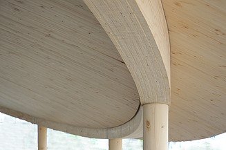 LENO-KIT from ZÜBLIN Timber Photo of a curved ceiling view. You can see wide, glued laminated veneer lumber beams.
