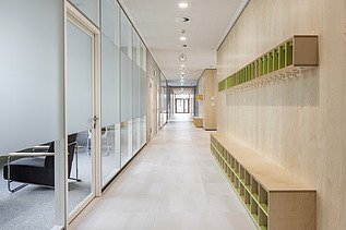 Innenaufnahme der Vinzenz-Pallotti-Schule in Friedberg. Man sieht einen Flur, eine Glas- und Holzwand und Aufbewahrungskisten an den Wänden.