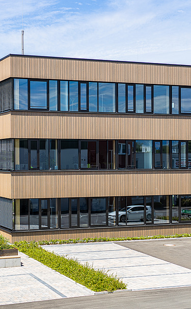 Foto eines Holzgebäudes mit Holz-Glasfassade und Flachdach.