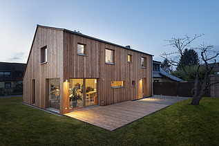 Photo of a modern wooden house. Dusk.
