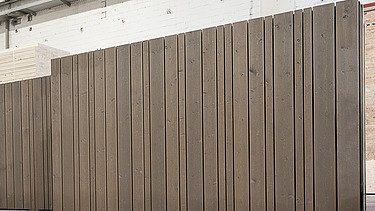 Photo of a standing LENO ADD exterior wall in the ZÜBLIN Timber production hall. It has a continuous timber façade installed.