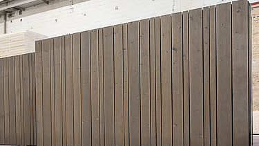Foto einer stehenden LENO-ADD-Außenwand in der Produktionshalle von ZÜBLIN Timber. Es  hat eine durchgängige Holzfassade montiert.