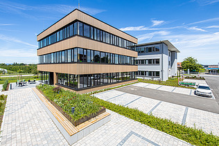 Foto eines Holzgebäudes mit Holz-Glasfassade und Flachdach.