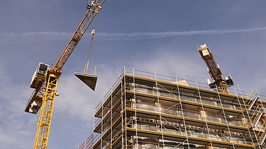 Foto des Rohbaus VINZENT in München. Zu sehen ist die Kranmontage eines Holzelements.