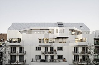 Photo of an exterior shot of a multi-storey building with a wooden extension. The building has a white façade.