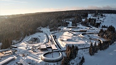 Photo of an aerial view with a snowy landscape and a curved bobsleigh run.