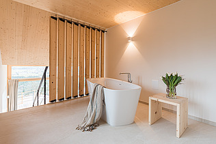 Foto eines Badezimmers. Man sieht eine Badewanne und viele Holzoberflächen.