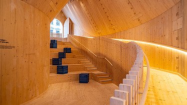 Foto des NEXT500-Pavillons auf dem Augsburger Marktplatz. Sie sehen eine moderne Inneneinrichtung aus Holz.