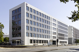Foto eines mehrgeschossigen Wohnungsbaus aus Holz mit weißer Fassade.